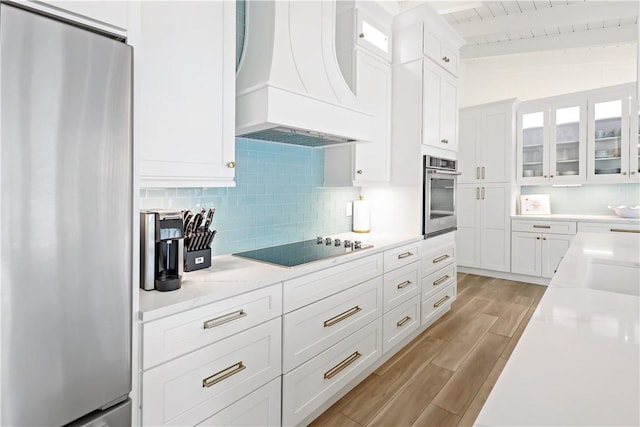 kitchen with appliances with stainless steel finishes, custom exhaust hood, white cabinets, and lofted ceiling with beams