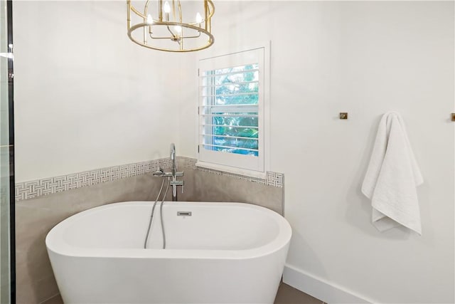 bathroom with a chandelier and a bath