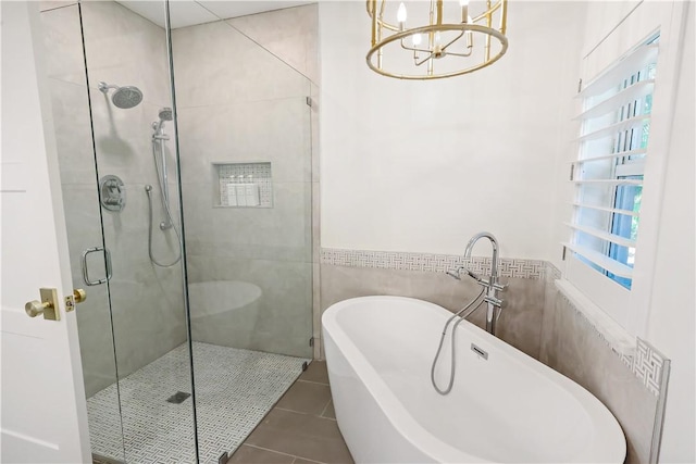 bathroom with tile walls, shower with separate bathtub, tile patterned floors, and a notable chandelier