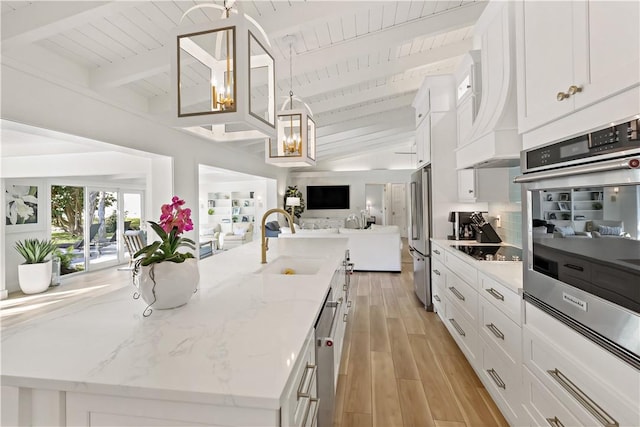 kitchen featuring light stone counters, an island with sink, light wood-type flooring, white cabinets, and sink