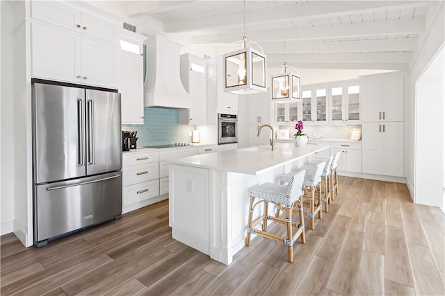 kitchen featuring wooden ceiling, an island with sink, custom exhaust hood, hanging light fixtures, and appliances with stainless steel finishes