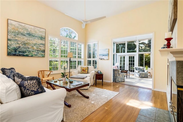 living room with hardwood / wood-style floors, a towering ceiling, a high end fireplace, and french doors