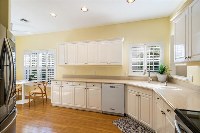 kitchen with a healthy amount of sunlight, sink, white cabinets, and appliances with stainless steel finishes