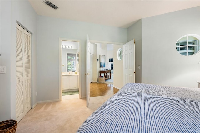 carpeted bedroom with ensuite bath and a closet