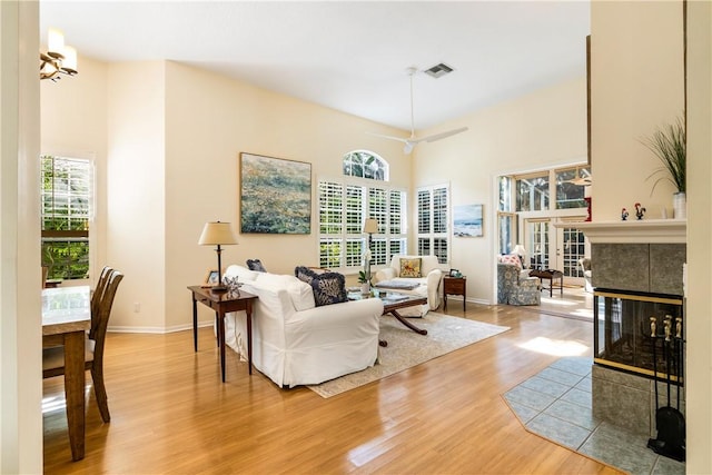 living room with wood-type flooring, a fireplace, and a high ceiling