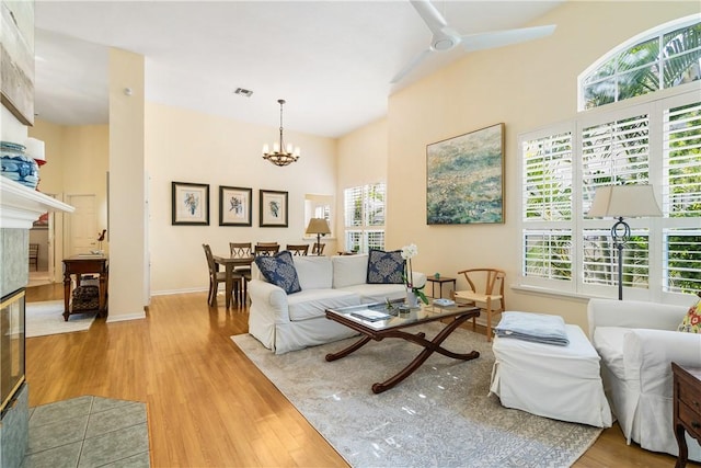 living room featuring ceiling fan with notable chandelier, a towering ceiling, and hardwood / wood-style floors