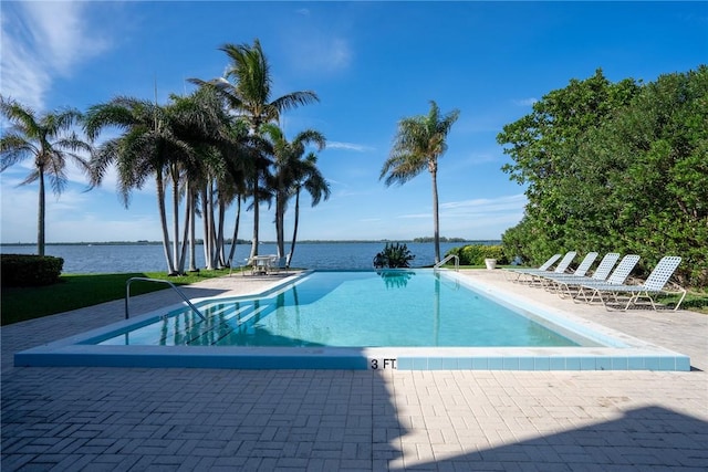 view of pool featuring a patio area and a water view