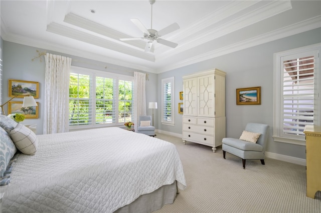 bedroom with light carpet, a ceiling fan, baseboards, a tray ceiling, and crown molding