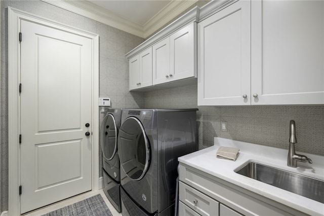 washroom featuring cabinet space, ornamental molding, a sink, washing machine and dryer, and tile walls