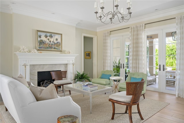 sitting room with a chandelier, a fireplace, wood finished floors, french doors, and crown molding