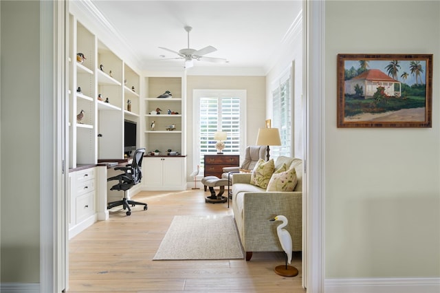 office area with ornamental molding, ceiling fan, built in desk, and light wood finished floors