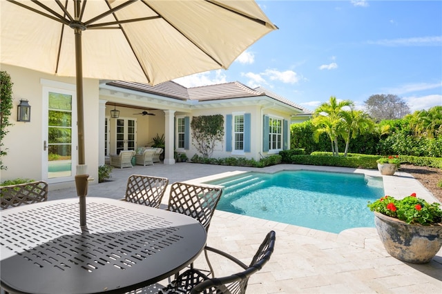 pool with outdoor dining area, a patio area, ceiling fan, and french doors