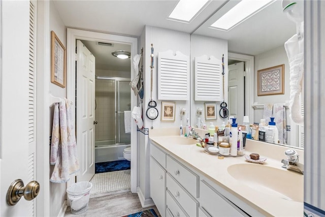 full bathroom with vanity, toilet, shower / bath combination with glass door, and a skylight