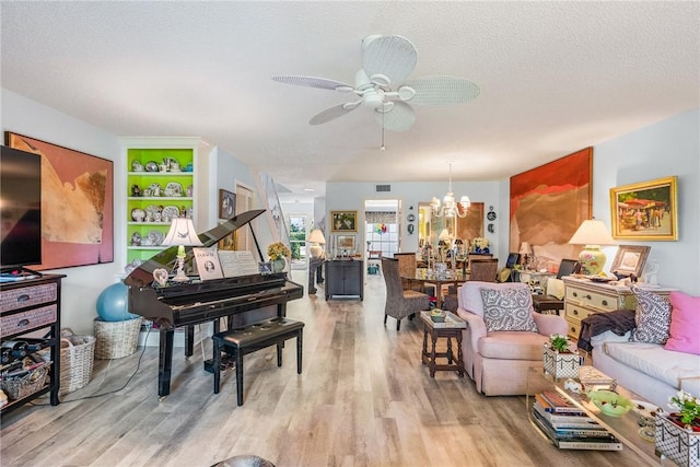 living room with ceiling fan with notable chandelier, a textured ceiling, and light wood-type flooring