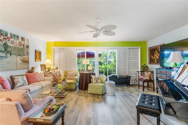 living room featuring hardwood / wood-style flooring, ceiling fan, and a textured ceiling