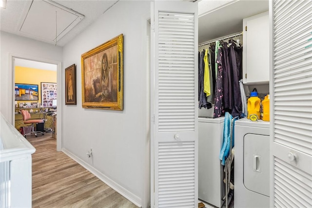 clothes washing area with washing machine and dryer and light hardwood / wood-style flooring