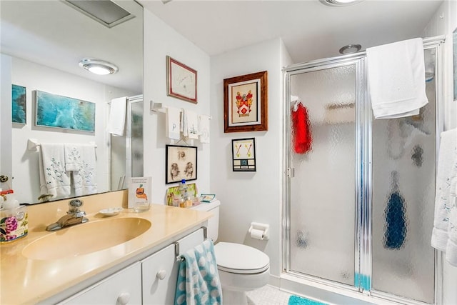 bathroom featuring vanity, a shower with shower door, and toilet