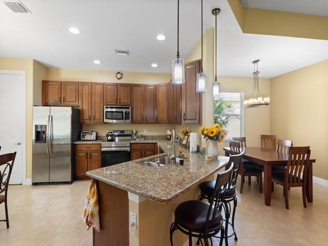 kitchen with appliances with stainless steel finishes, kitchen peninsula, sink, and hanging light fixtures