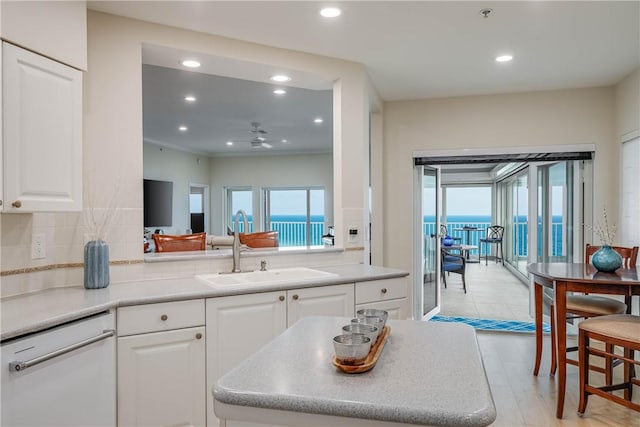 kitchen with sink, white dishwasher, tasteful backsplash, white cabinets, and kitchen peninsula