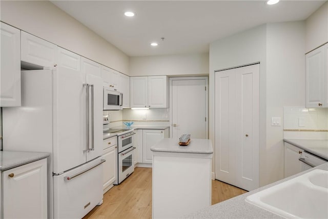 kitchen with white cabinetry, white appliances, and a center island