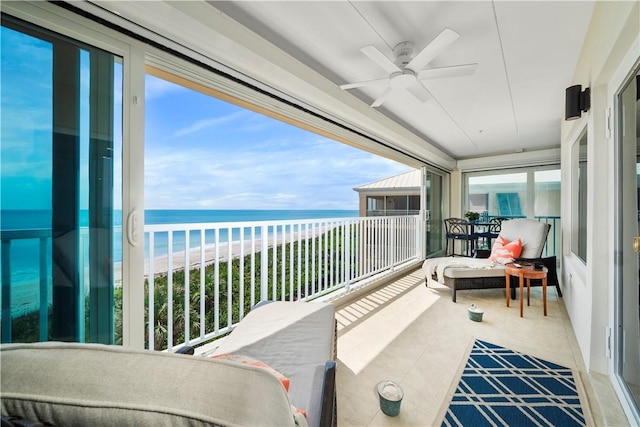 balcony with a view of the beach, ceiling fan, and a water view