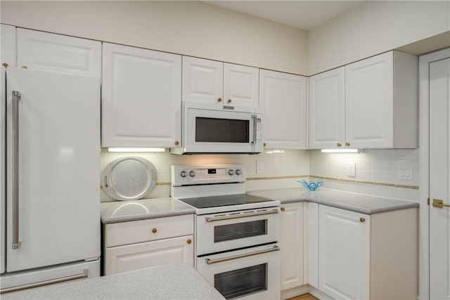 kitchen featuring white cabinetry, backsplash, and white appliances