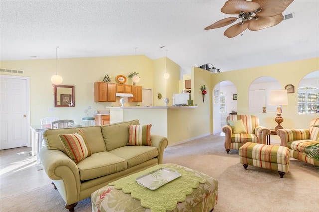 living room with a textured ceiling, ceiling fan, light carpet, and lofted ceiling