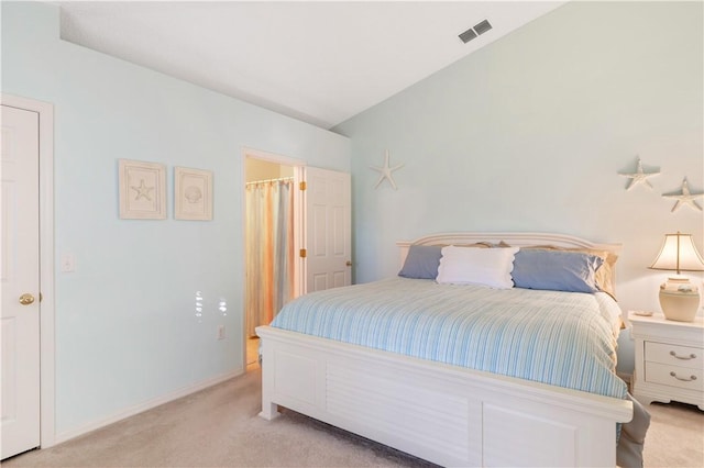 bedroom with ensuite bathroom and light colored carpet