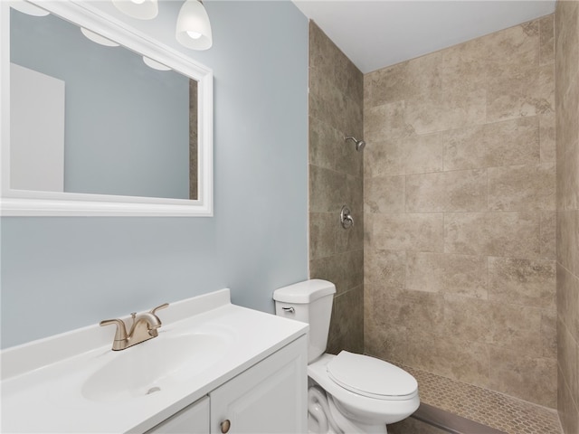 bathroom featuring toilet, vanity, and tiled shower