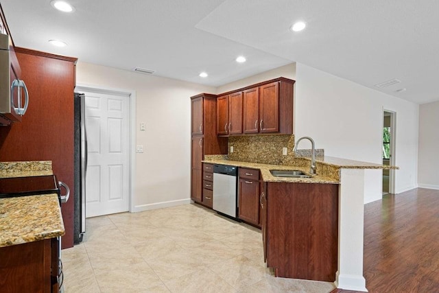 kitchen featuring light stone countertops, sink, backsplash, kitchen peninsula, and appliances with stainless steel finishes