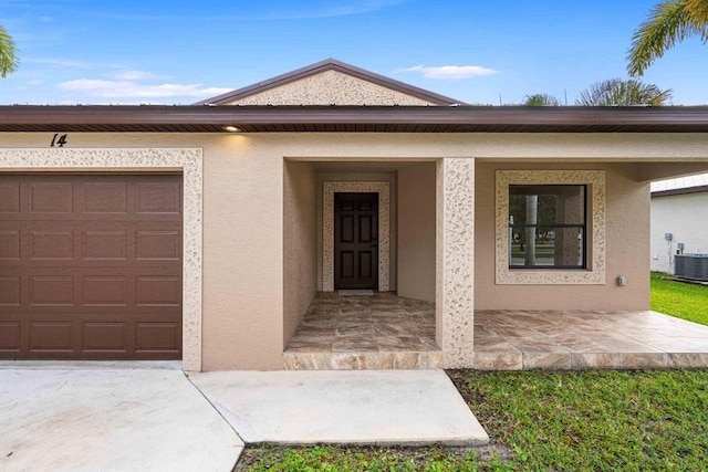 doorway to property with covered porch, a garage, and central air condition unit