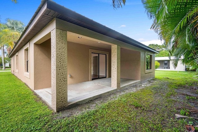 back of property featuring a lawn and a patio