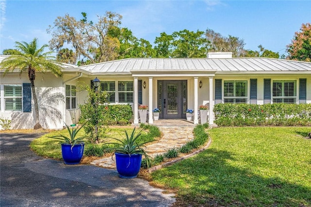 ranch-style house with metal roof, a front lawn, and a standing seam roof