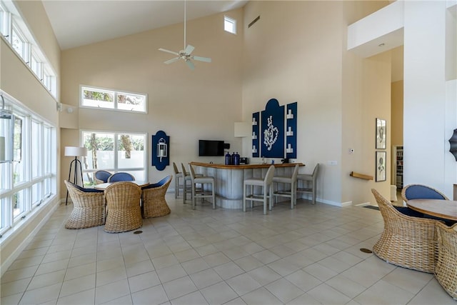 interior space with a high ceiling, ceiling fan, and light tile patterned flooring