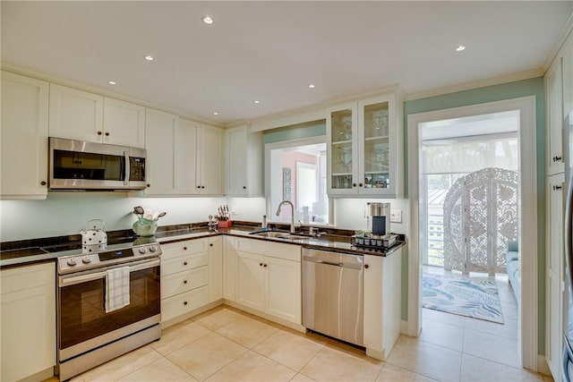 kitchen with stainless steel appliances, sink, white cabinetry, ornamental molding, and light tile patterned floors