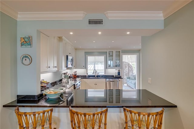 kitchen with kitchen peninsula, a breakfast bar, white cabinets, and stainless steel appliances