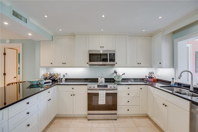 kitchen with appliances with stainless steel finishes, white cabinetry, light tile patterned floors, and sink