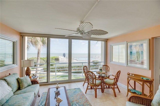 sunroom with ceiling fan and a water view