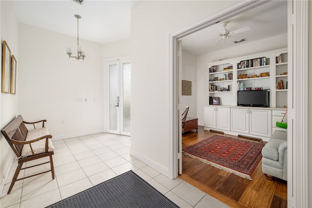 sitting room with light tile patterned floors, ceiling fan with notable chandelier, visible vents, and baseboards