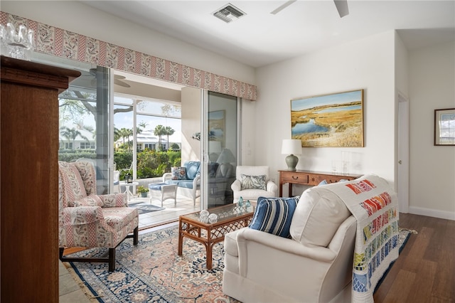 living area featuring a ceiling fan, visible vents, baseboards, and wood finished floors