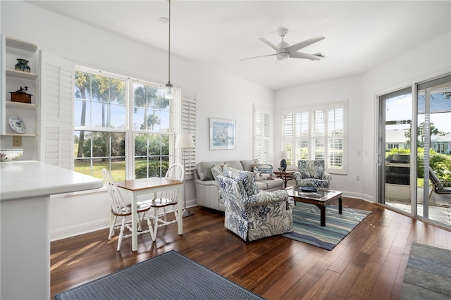 living room with dark wood-type flooring, ceiling fan, and baseboards