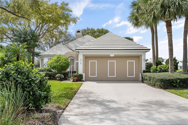 view of front facade featuring an attached garage, a chimney, concrete driveway, and stucco siding