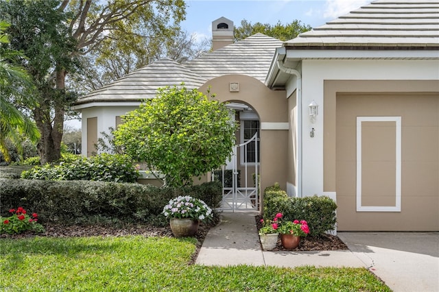 property entrance with a chimney and stucco siding