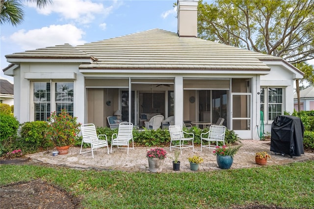 rear view of house with a chimney, a patio area, and a sunroom