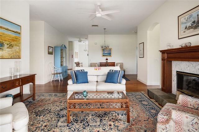 living room with ceiling fan, arched walkways, a premium fireplace, wood finished floors, and visible vents