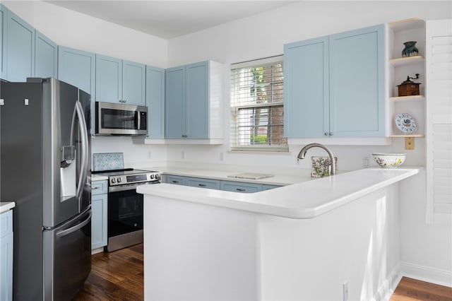 kitchen with dark wood-style floors, open shelves, appliances with stainless steel finishes, blue cabinets, and a peninsula