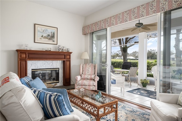 sitting room with a fireplace, wood finished floors, and a ceiling fan