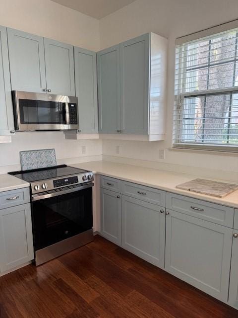 kitchen featuring stainless steel appliances, dark wood-style flooring, and light countertops