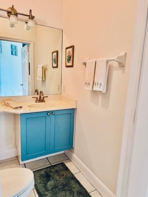 half bath featuring baseboards, vanity, toilet, and tile patterned floors