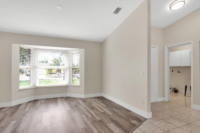 empty room featuring lofted ceiling and light hardwood / wood-style floors